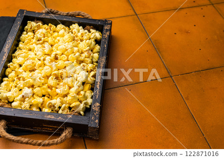Cheese and salty popcorn in wooden tray. orange background. top view Cheese and salty popcorn in wooden tray. orange background. top view 122871016