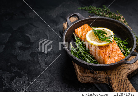 Fried salmon fillet with herbs, grilled fish steak in a pan. black background. top view Fried salmon fillet with herbs, grilled fish steak in a pan. black background. top view 122871082