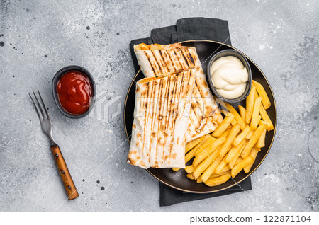 Chicken Fajita wrap sandwich with fresh salad and french fry on a plate. gray background. top view Chicken Fajita wrap sandwich with fresh salad and french fry on a plate. gray background. top view 122871104