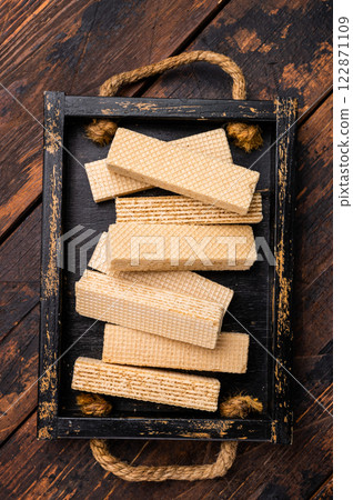 Wafer stick biscuits with vanilla cream in wooden tray. wooden background. top view 122871109