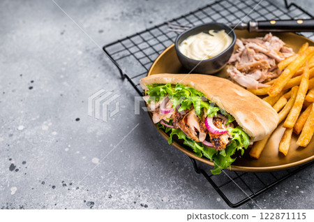 Grilled shawarma sandwich, Doner kebab with grilled meat in pita bread on a plate with french fry. grey background. top view Grilled shawarma sandwich, Doner kebab with grilled meat in pita bread on a plate with french fry. grey background. top view 122871115
