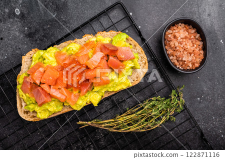 Toast with salty salmon, trout slices, avocado and red caviar. black background. top view 122871116