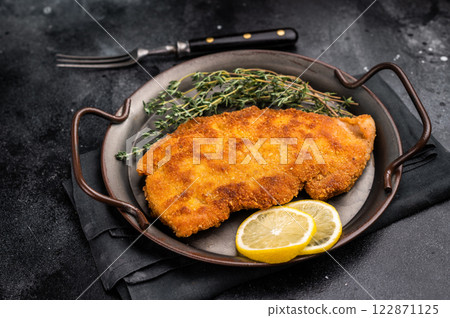 German Wiener schnitzel steak, breaded pork fillet meat. black background. top view 122871125
