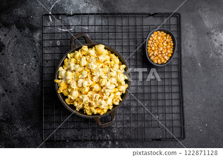 Delicious cheese and salted popcorn in a skillet . black background. top view Delicious cheese and salted popcorn in a skillet . black background. top view 122871128