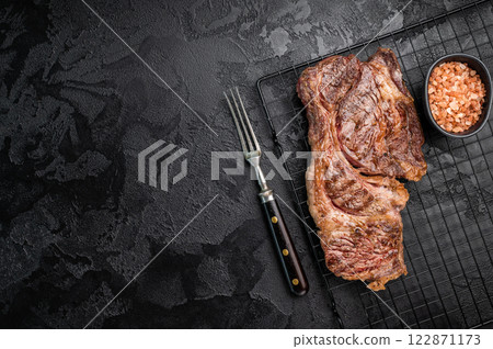 BBQ grilled Chuck eye roll steak, prime beef meat on a steel rack. black background. top view 122871173
