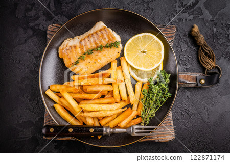 Homemade Fish and chips with roast cod whitefish fillet and fried potatoes on plate. black background. top view Homemade Fish and chips with roast cod whitefish fillet and fried potatoes on plate. black background. top view 122871174