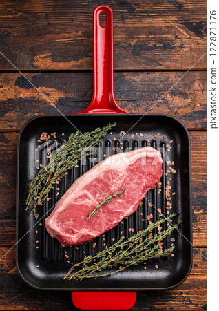 Fresh strip loin beef steak, striploin steak on a grill pan wooden background. top view Fresh strip loin beef steak, striploin steak on a grill pan wooden background. top view 122871176