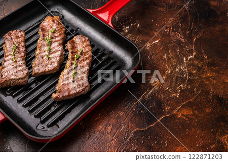 Grilled Tri tip steaks, marbled beef meat on pan with herbs. brown background. top view Grilled Tri tip steaks, marbled beef meat on pan with herbs. brown background. top view 122871203