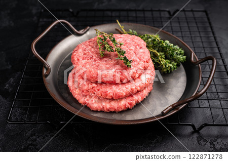 Stack of Raw meat patties, cutlets, chopped meat for burgers in stell tray with herbs. black background. top view Stack of Raw meat patties, cutlets, chopped meat for burgers in stell tray with herbs. black background. top view 122871278