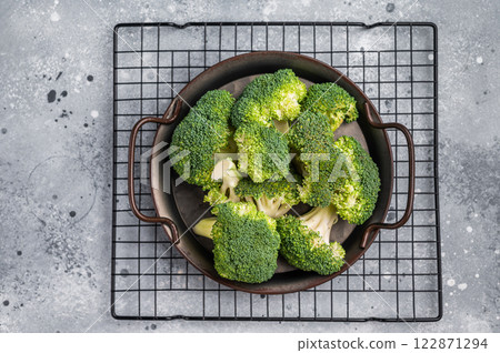 Green fresh broccoli pieces in a steel tray. grey background. top view Green fresh broccoli pieces in a steel tray. grey background. top view 122871294
