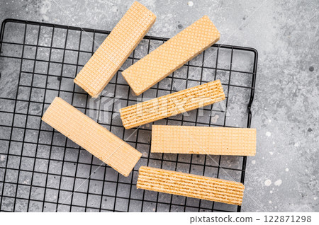 Dry Wafer stick biscuits with vanilla cream on a rack. grey background. top view Dry Wafer stick biscuits with vanilla cream on a rack. grey background. top view 122871298