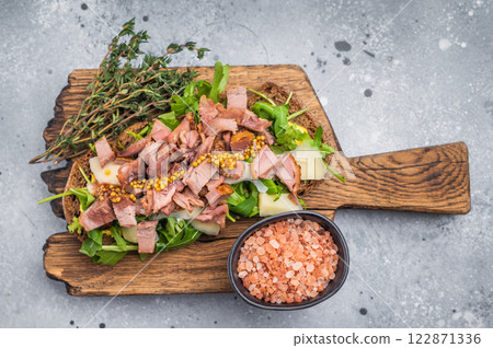 Open sandwich with duck fillet meat, foie gra liver, arugula and cheese on board. grey background. top view Open sandwich with duck fillet meat, foie gra liver, arugula and cheese on board. grey background. top view 122871336