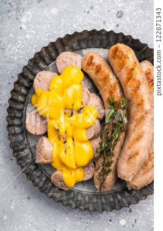 Grilled Bratwurst Sausages with cheese sauce in plate. grey background. top view 122871343