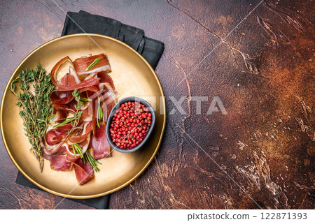 Cured duck fillet meat slices, magret smoked poultry on a plate. brown background. top view 122871393