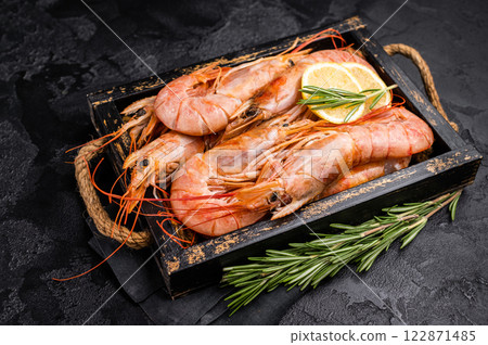 Uncooked raw Red shrimps, Prawns Langostino Austral in wooden tray. black background. top view Uncooked raw Red shrimps, Prawns Langostino Austral in wooden tray. black background. top view 122871485
