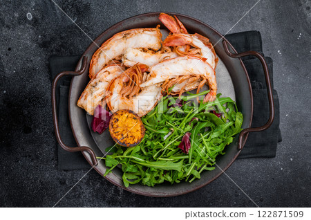 Grilled Jumbo Shrimps Prawns on a plate with salad. black background. top view Grilled Jumbo Shrimps Prawns on a plate with salad. black background. top view 122871509