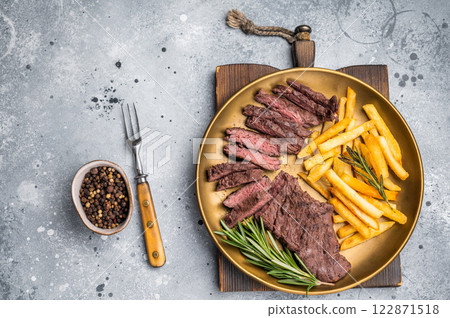 BBQ Grilled Beef Skirt Machete Steak on a plate with french fries grey background. top view BBQ Grilled Beef Skirt Machete Steak on a plate with french fries grey background. top view 122871518
