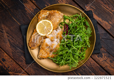 Roasted Pollock fish fillet on a plate with salad. wooden background. top view 122871521