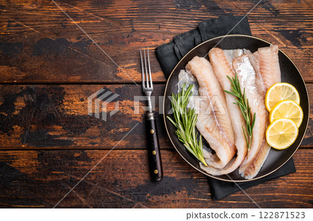 Organic Raw Haddock fish fillets, whitefish on a plate with herbs. wooden background. top view 122871523