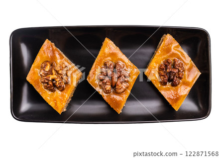 Homemade Walnut Baklava with honey on plate isolated on white background. top view Homemade Walnut Baklava with honey on plate isolated on white background. top view 122871568