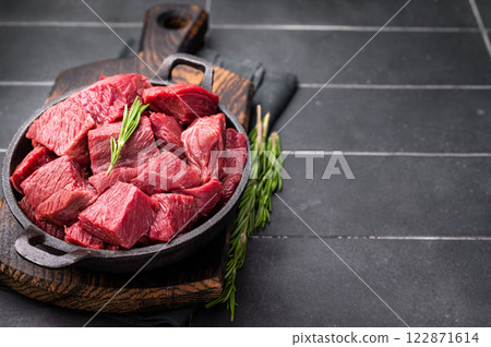 Diced Raw Ostrich meat, uncooked Game Meat in a skillet. black background. top view 122871614