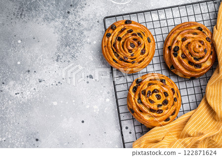 Baked Danish pastry, raisin bun on steel rack. grey background. top view 122871624