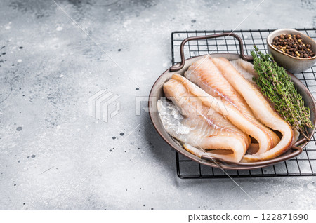 Raw Hake fish fillet in steel tray with herbs. grey background. top view Raw Hake fish fillet in steel tray with herbs. grey background. top view 122871690