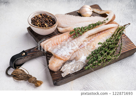 fresh Raw Pollock fish fillets on a wooden board with herbs. white background. top view fresh Raw Pollock fish fillets on a wooden board with herbs. white background. top view 122871693