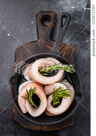 Ready for cooking Raw Pollock fish fillets in pan with herbs. black background. top view 122871707