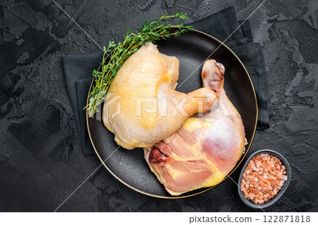 Chicken legs in a plate with herbs, farm poultry raw meat on black background, top view Chicken legs in a plate with herbs, farm poultry raw meat on black background, top view 122871818