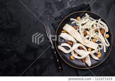 Smoked Traditional Chechil white cheese on a plate with nuts, black background. 122871819