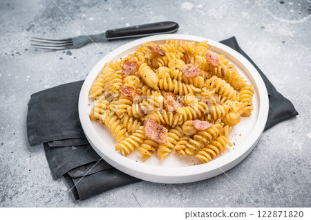 Carbonara pasta topped with crispy bacon bits and parmesan cheese in a plate. Gray background. Top view 122871820