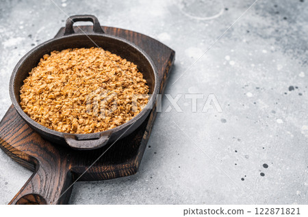 Raw buckwheat flakes in a skillet. grey background. top view Raw buckwheat flakes in a skillet. grey background. top view 122871821