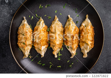 Fried Japanese Gyoza Dumplings with meat and vegetables on plate. black background. top view Fried Japanese Gyoza Dumplings with meat and vegetables on plate. black background. top view 122871822