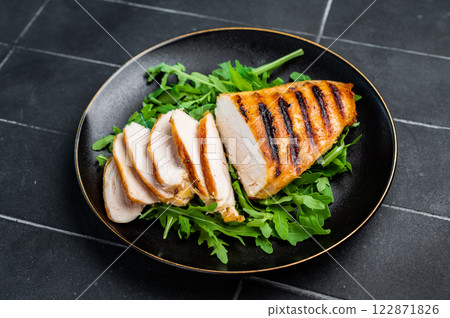 Grilled Chicken breasts on a plate with salad, fried poultry meat steaks, top view, black background. 122871826