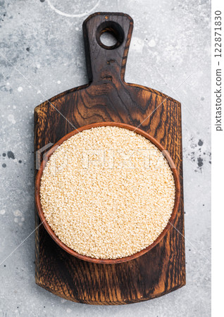 White sesame seeds in a wooden bowl. grey background. top view 122871830