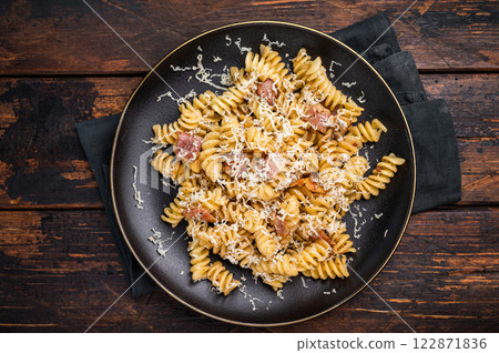 Italian Carbonara pasta topped with crispy bacon bits in a plate. Wooden background. Top view Italian Carbonara pasta topped with crispy bacon bits in a plate. Wooden background. Top view 122871836
