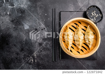 Steamed Japanese Gyoza Dumplings with pork meat and vegetables in bamboo steamer. black background. top view 122871842
