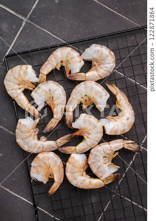 Raw shrimps, headless fresh prawns on a rack. Top view. Black background 122871864