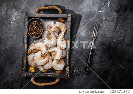 Fresh Raw headless tiger shrimps prawns in a tray. Top view. Black background 122871872