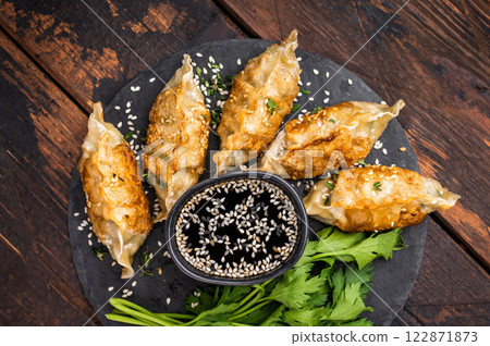 Fried Gyoza on plate with sauce, Japanese Dumplings with shrimps and vegetables. wooden background. top view 122871873