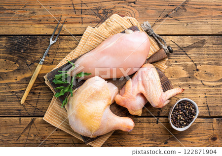 Raw chicken breast, legs, and wings on a wooden cutting board, ready for cooking 122871904