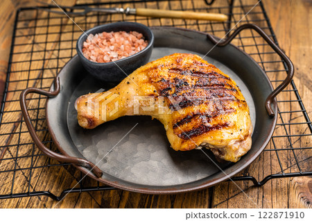 Grilled chicken leg or quarter in a skillet, roasted poultry meat on black background, top view. Grilled chicken leg or quarter in a skillet, roasted poultry meat on black background, top view. 122871910