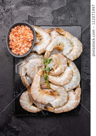 Raw headless white shrimps prawns on a marble board. Top view. Black background 122871997
