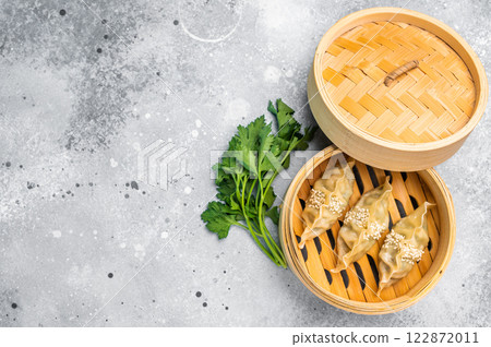 Steamed Jiaozi Chinese Dumplings with meat and vegetables in bamboo steamer. grey background. top view 122872011