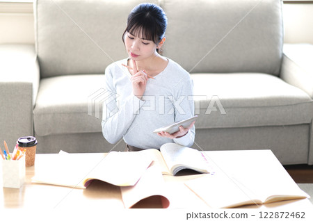 一位年輕女子獨自在客廳學習 一位年輕女子獨自在客廳學習 122872462