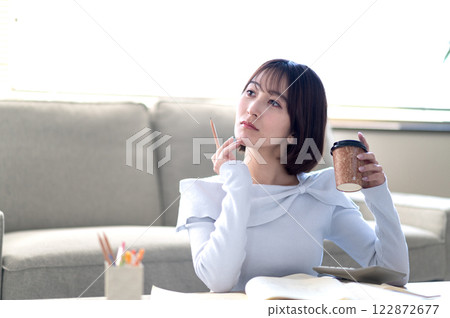 一位年輕女子獨自在客廳學習 一位年輕女子獨自在客廳學習 122872677