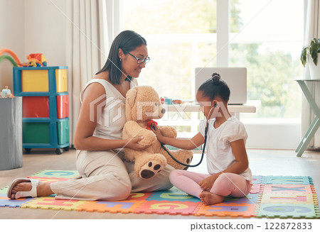 Kindergarten, education and stethoscope with teacher and girl playing doctor game with teddy bear for development, learning and care. Classroom, wellness and therapist with young student and woman 122872833