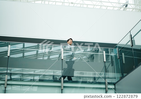 A young businessman in sales walking through a beautiful building A young businessman in sales walking through a beautiful building 122872879