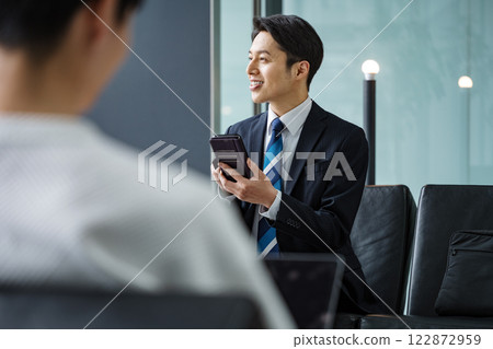 Businessman using smartphone app in lobby 122872959
